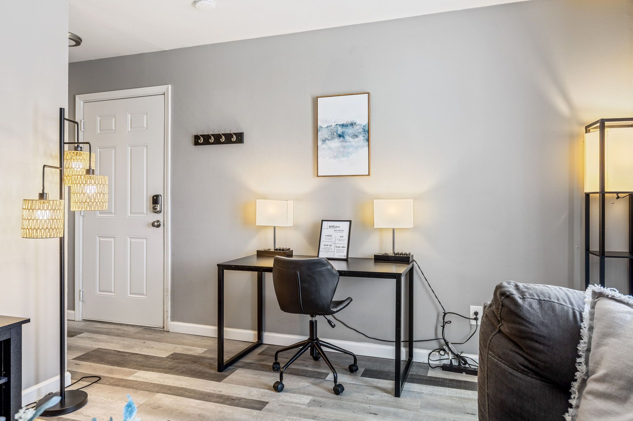 A modern living room with a black leather chair, a desk, and two wall-mounted lamps.