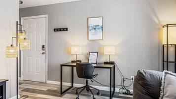 A modern living room with a black leather chair, a desk, and two wall-mounted lamps.
