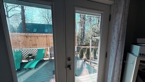 A room with a sliding glass door leading to an outdoor deck with a wooden fence, a green lawn chair, and a table. - Spacious family sized beach home - 15 minute walk to beach! (Old Orchard Beach)
