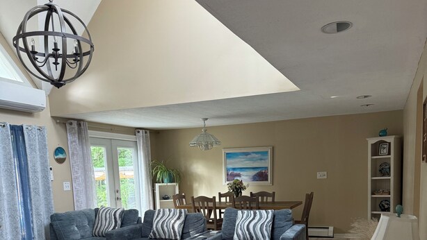 A spacious living room with a sectional sofa, a wooden coffee table, and a chandelier. - Spacious family sized beach home - 15 minute walk to beach! (Old Orchard Beach)