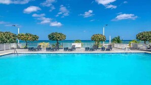 Ein Swimmingpool mit Liegestühlen und Blick aufs Meer.