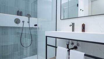 Une salle de bain moderne avec une douche à parois de verre, un lavabo blanc doté d’un cadre noir et un miroir au-dessus du lavabo.