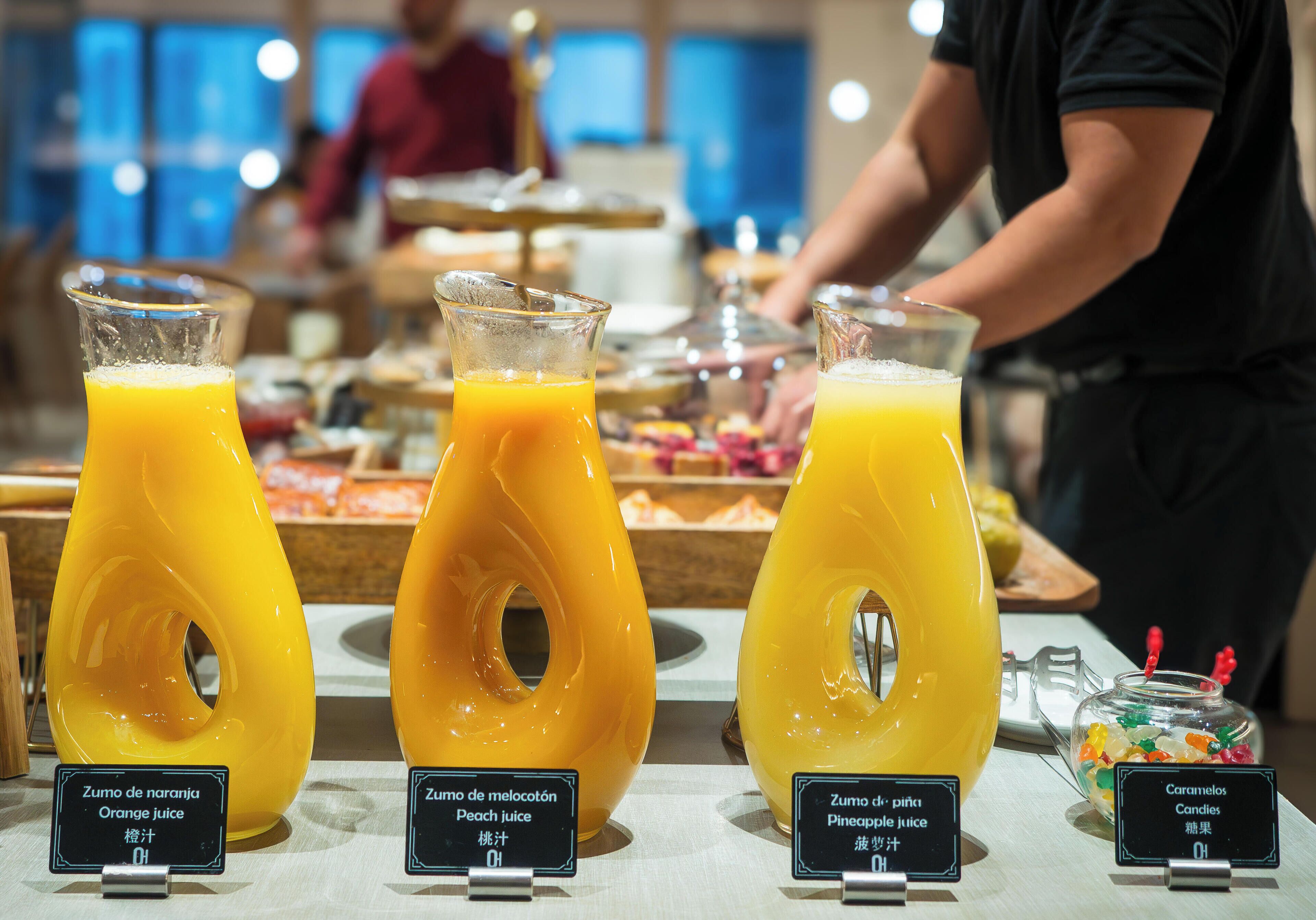 Ein Frühstücksbuffet mit Orangensaft, Pfirsichsaft und Ananassaft sowie einer Süßigkeitenpräsentation.