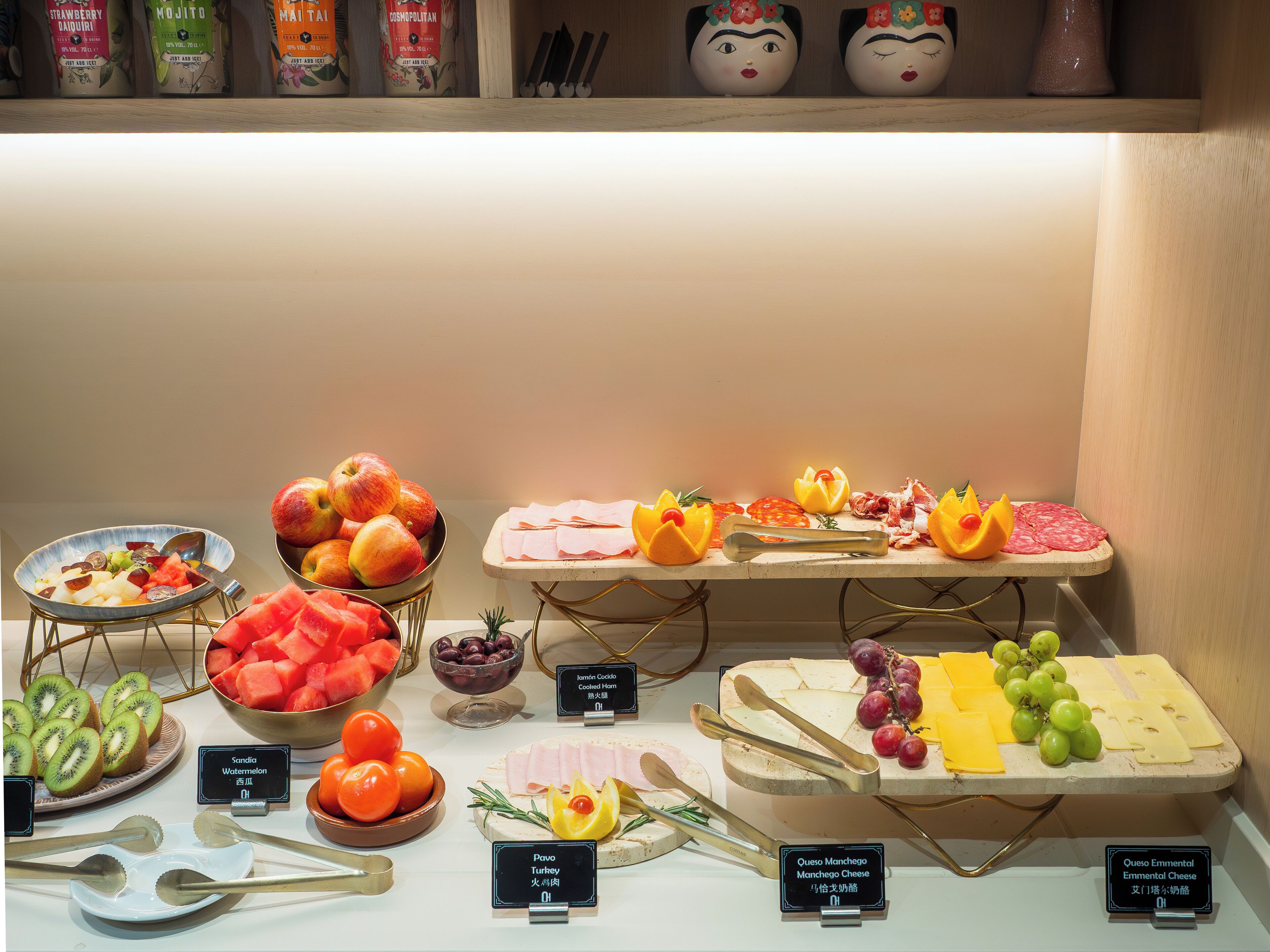 Diversos productos alimenticios como frutas, quesos y embutidos expuestos en una barra.