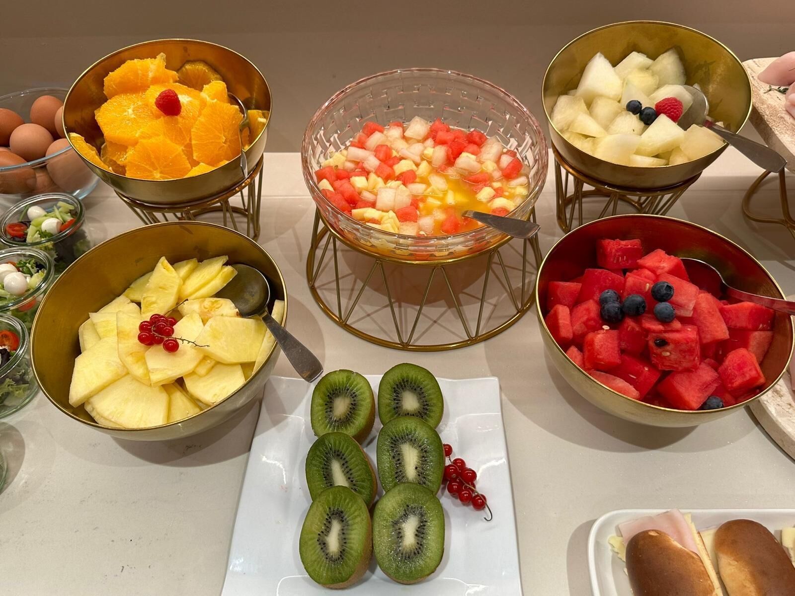 Un bufé con diversas frutas y un plato de kiwi en rodajas.
