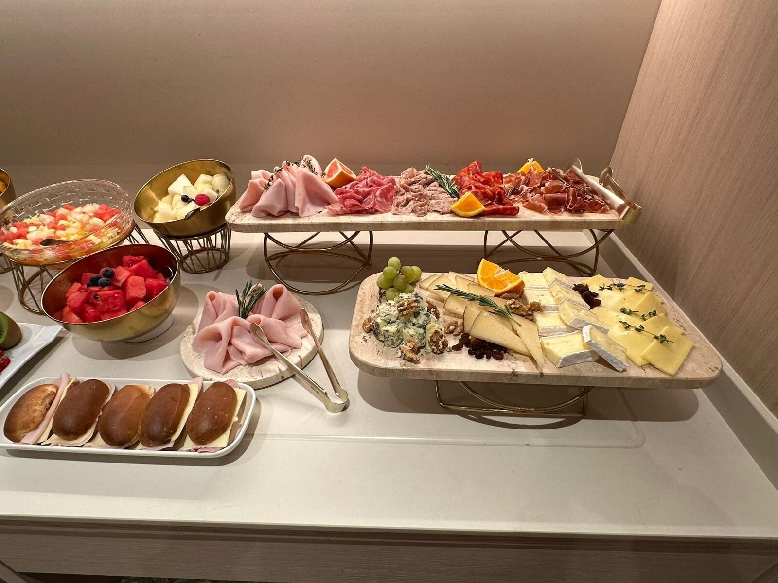 Una mesa de buffet con diferentes opciones de comida, como carnes, quesos, frutas y pasteles.