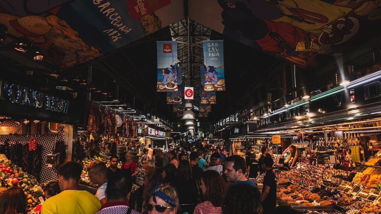 A bustling indoor market with various stalls selling fruits and vegetables.