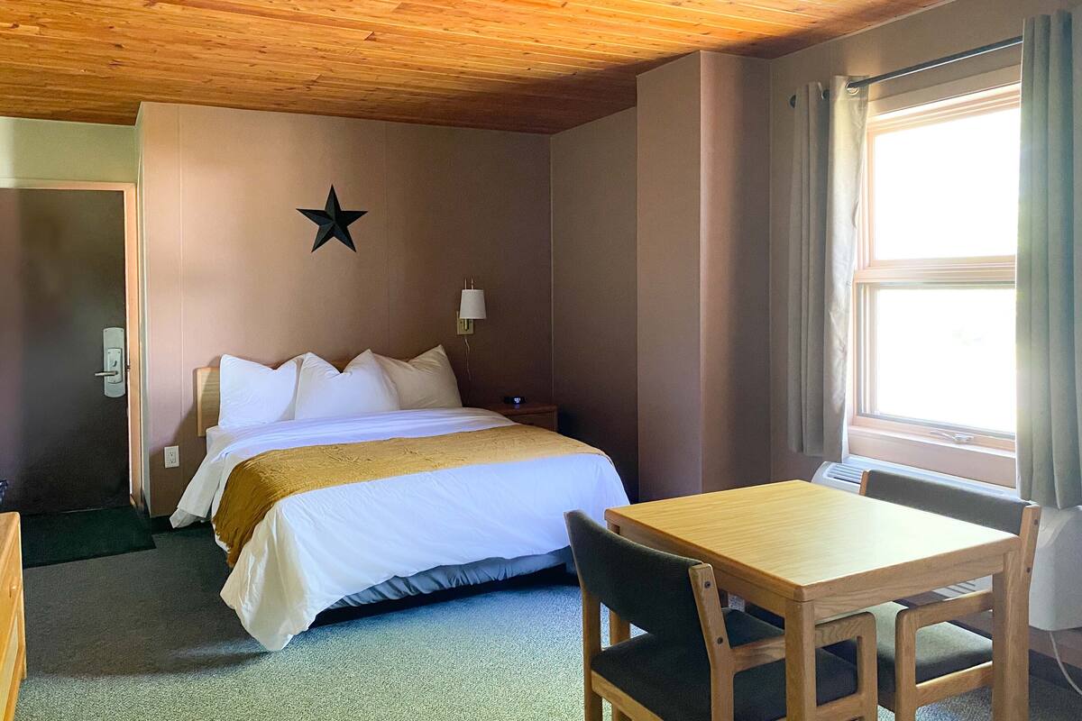 A hotel room with a bed, a wooden table, and a star decoration on the wall.