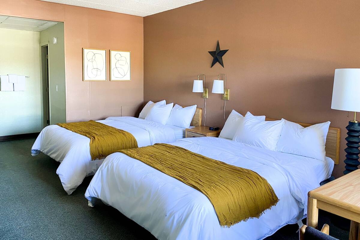 A hotel room with two beds, a star decoration on the wall, and two bedside lamps.