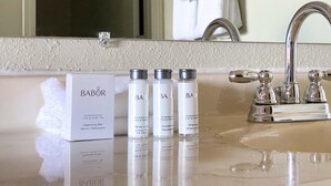 A bathroom with a mirror, a sink, and three Babolat body care products. - The Benson Motel - Benson, MN - US-12 HWY (Benson)
