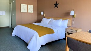 A hotel room with a bed, bedside tables, a desk, and a chair. - The Benson Motel - Benson, MN - US-12 HWY (Benson)