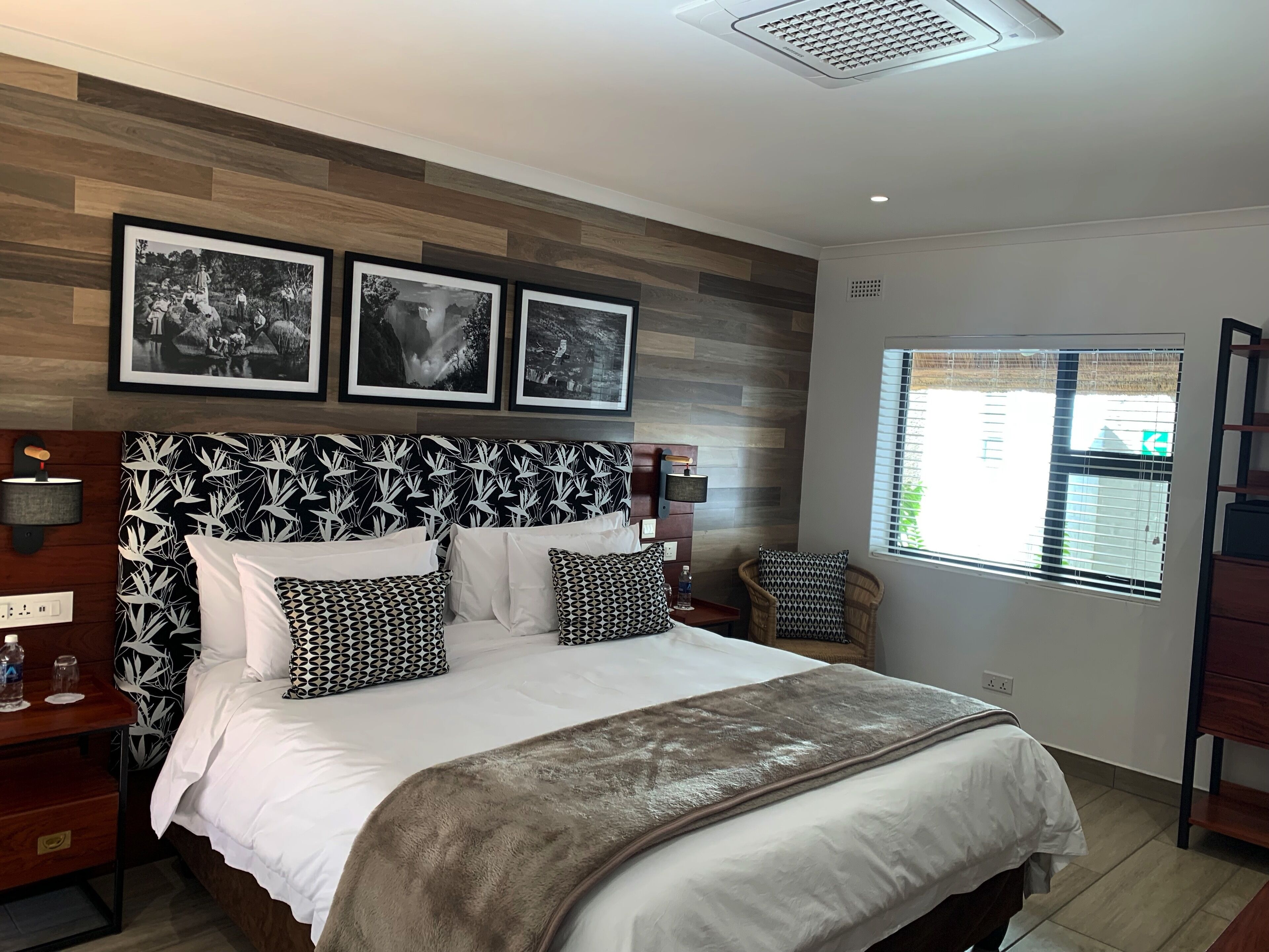 A bedroom with a bed, a nightstand, a lamp, and three framed pictures on the wall.
