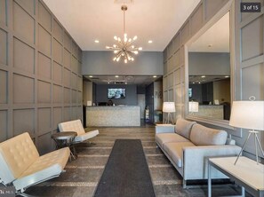 Relax in our spacious lobby, featuring a comfortable seating area with a sofa and armchairs, a reception desk, and a large mirror.