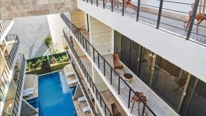 A multi-level hotel with a central pool, balconies with seating, and a view of the sky. - Sherlock - Swim up Suite & Gym & Beach Club Access (Tulum)