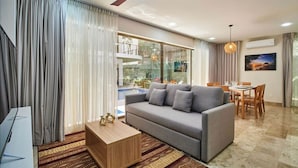 A modern living room with a sofa, coffee table, and dining area. - Sherlock - Swim up Suite & Gym & Beach Club Access (Tulum)