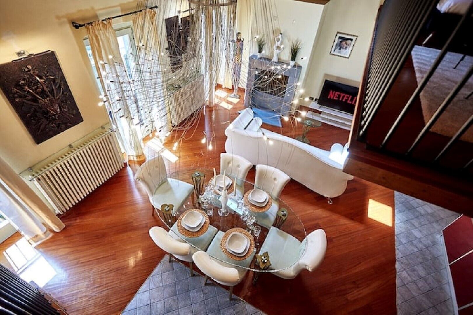 A dining area with a round table, white chairs, and a modern chandelier.