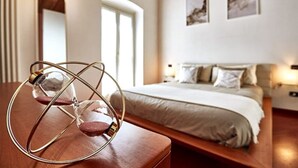 A bedroom with a large bed, a bedside table with a lamp, and two framed pictures on the wall. - Luxury Design Loft - [Piazza Pontida] (Bergamo)