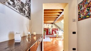 A hallway with a wooden desk, a framed picture, and a staircase leading to a dining area. - Luxury Design Loft - [Piazza Pontida] (Bergamo)