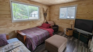 Une chambre confortable dans un chalet, avec deux lits, une télévision et une petite table.