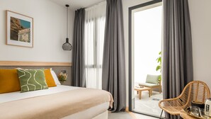 Una habitación de hotel moderna con cama, zona de comedor y vistas al exterior.