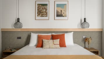 Cama bem arrumada com cabeceira de madeira, duas imagens emolduradas na parede e duas luminárias pendentes.