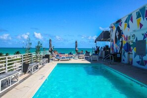 A pool area with lounge chairs, a railing, and a view of the ocean. - Miami Ocean Drive 1BR APT & Rooftop Pool Access (Miami Beach)