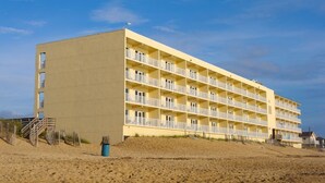 A multi-story hotel with balconies, located on a sandy beach. - SRQ1 Enjoy unbeatable ocean views from the private balcony terrace, or oceanfront bedroom. (Kill Devil Hills)
