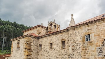 A historic stone building with a tiled roof, arched windows, and a bell tower.