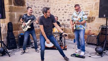 Una banda tocando en un escenario con un fondo de pared de piedra, rodeada de equipo musical.