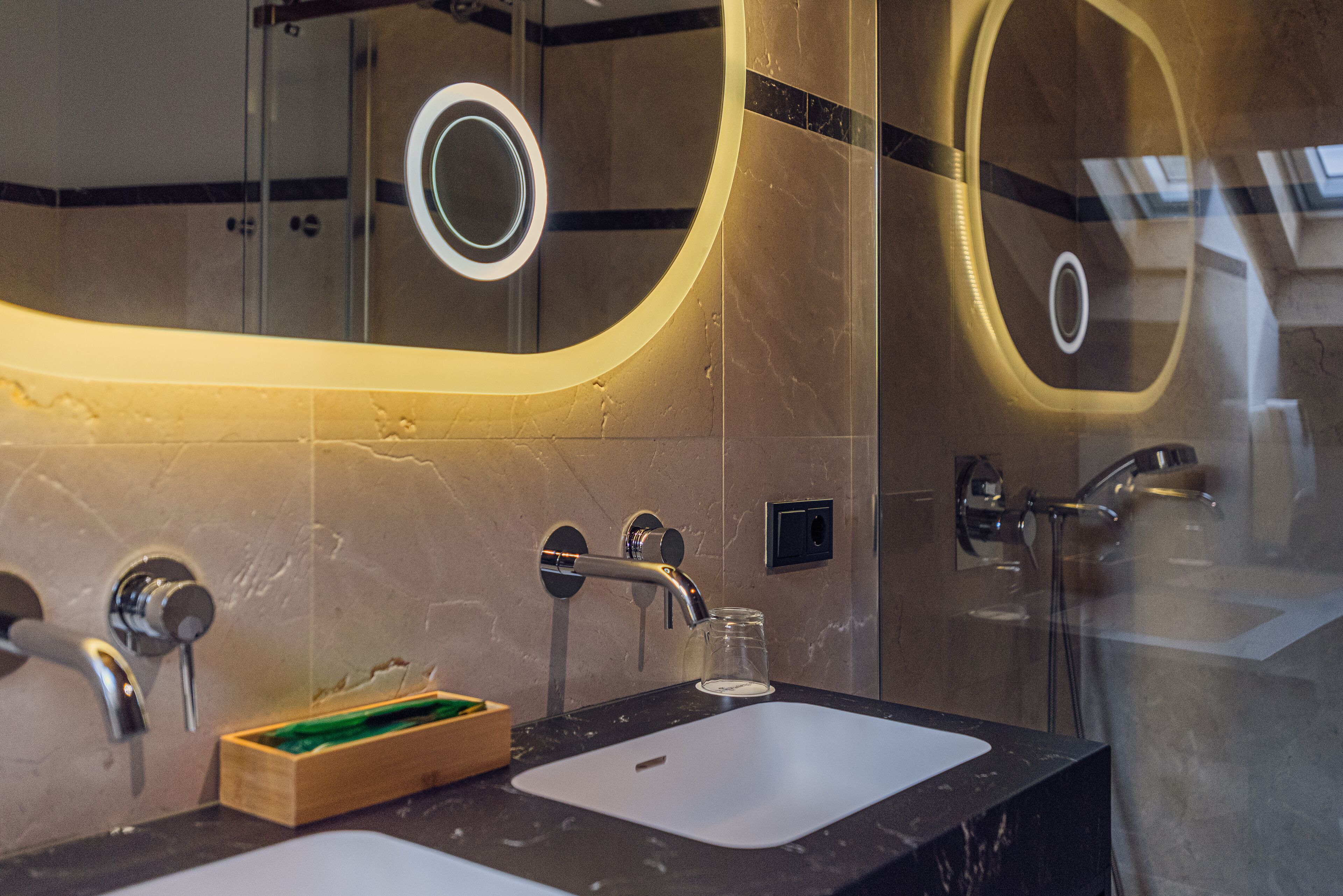 A modern bathroom with a large mirror, a sink, and a glass shower enclosure.