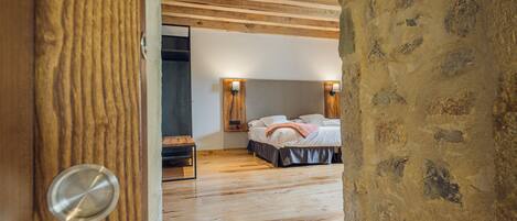 A bedroom with a wooden ceiling, a bed with a white comforter, and two wall-mounted lights.
