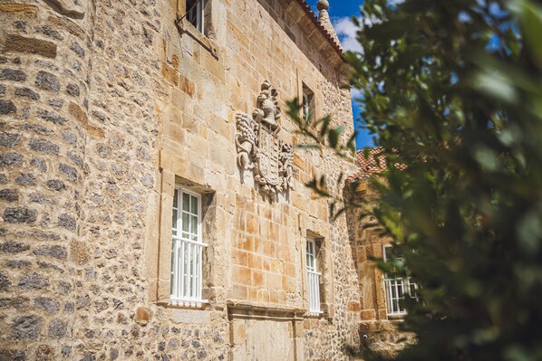 A stone building with two windows and a decorative stone carving.