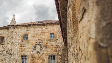 Un edificio de piedra con techo de tejas, varias ventanas y un escudo decorativo.
