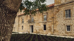 Un edificio de piedra con techo de tejas, balcón y jardín.