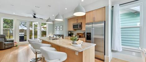 A modern kitchen with a central island, stainless steel appliances, and pendant lighting.