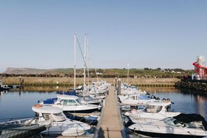 A marina with boats docked in calm waters, a clear sky, and a distant landscape. - North Coast 9 (Ballymoney)