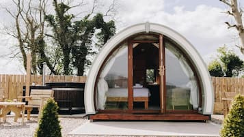 Una habitación con techo abovedado, una cama, un jacuzzi y una terraza de madera.