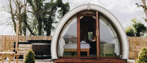 Una habitación con techo abovedado, una cama, un jacuzzi y una terraza de madera.