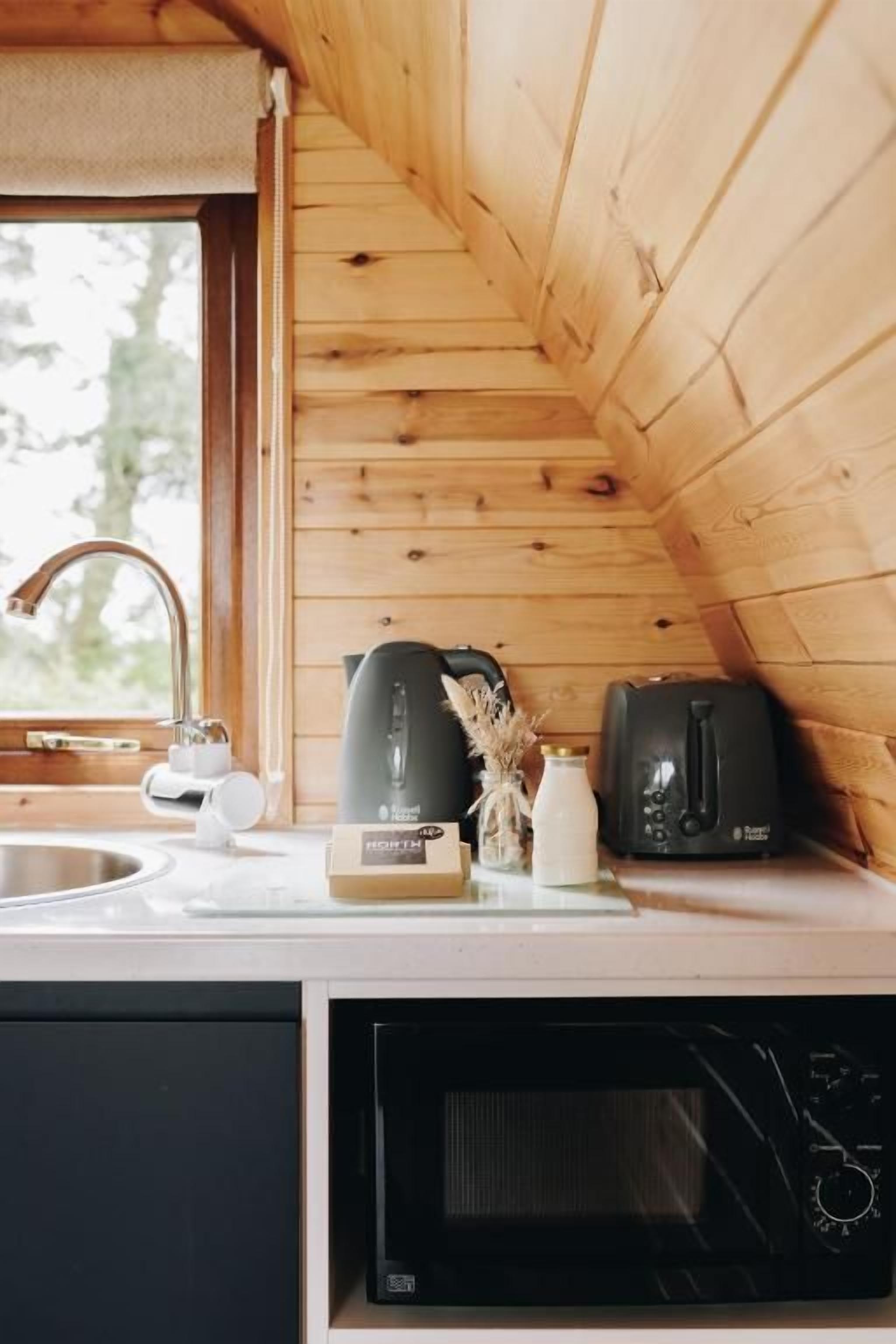 Una cocina con paredes de madera, microondas, tostadora y ventana.
