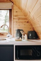 Una cocina con paredes de madera, microondas, tostadora y ventana.