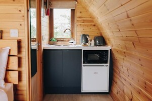 Una kitchenette compacta con microondas, tostadora y lavamanos.