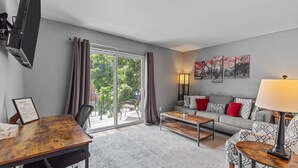 A modern living room with a sofa, coffee table, and a flat-screen TV mounted on the wall.