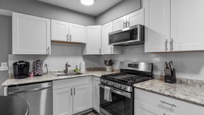 A modern kitchen with white cabinets, stainless steel appliances, and a granite countertop.