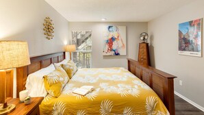 Ein Schlafzimmer mit Bett, Nachttischlampen, einem Nachttisch, einem Fenster mit Blick und Bildern an der Wand.