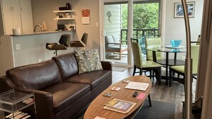 Ein modernes Wohnzimmer mit einer Ledersofa, einem Holztisch und einem Essbereich mit Glastisch und Stühlen.