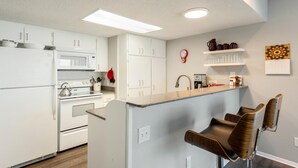 Eine moderne Küche mit weißen Schränken, einer Mikrowelle, einem Backofen und einer Frühstückstheke mit Barhocker.