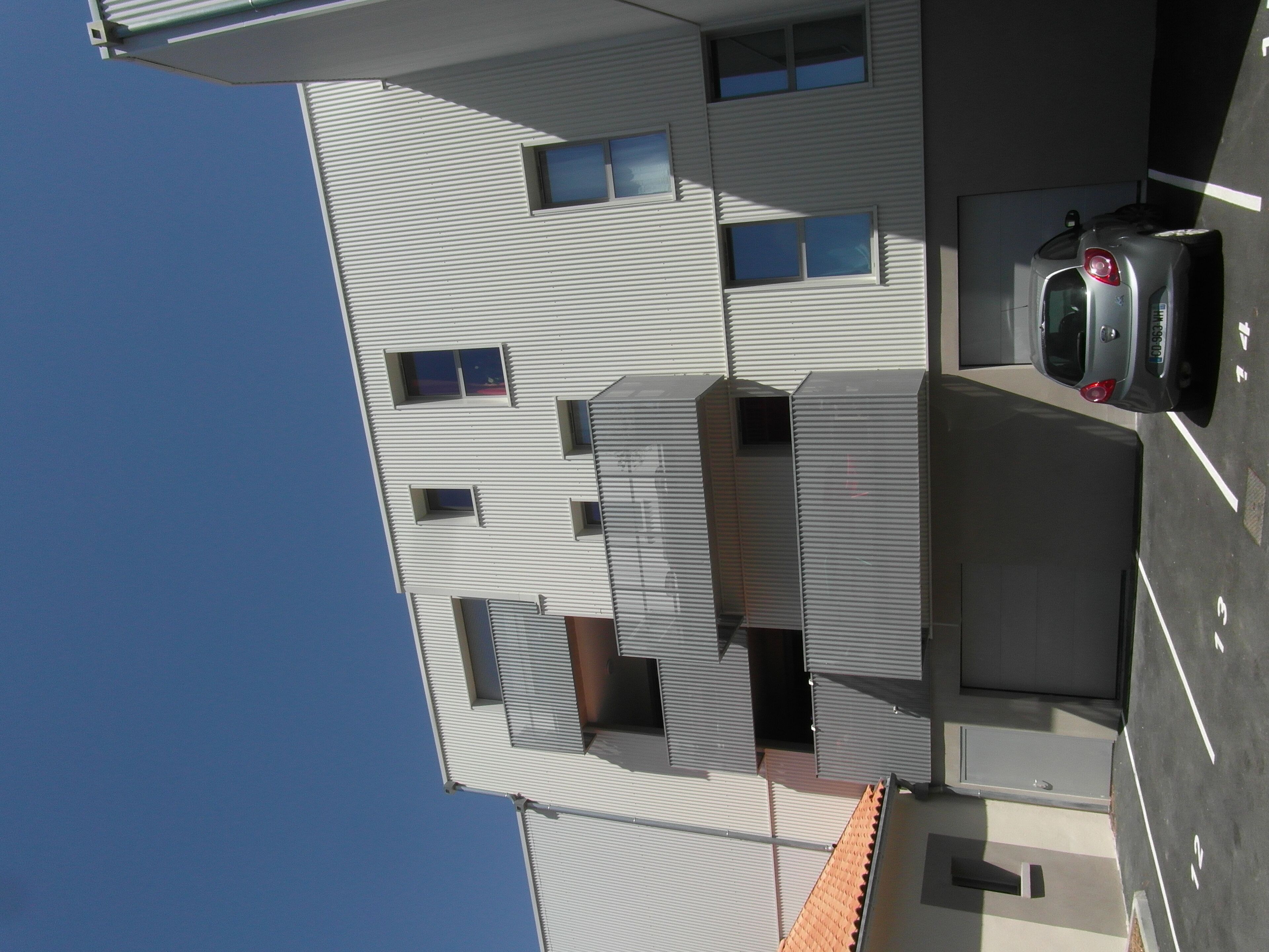 Un edificio de varios pisos con un estacionamiento.