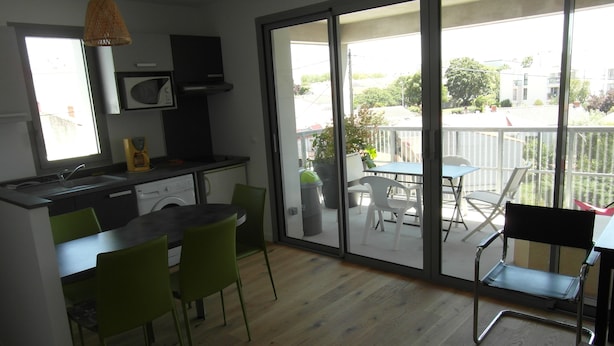 A modern kitchen with a dishwasher, a microwave, and a hanging light fixture. - Appt NEUF (2022) type 2 a 800 mètres ocean (La Rochelle)