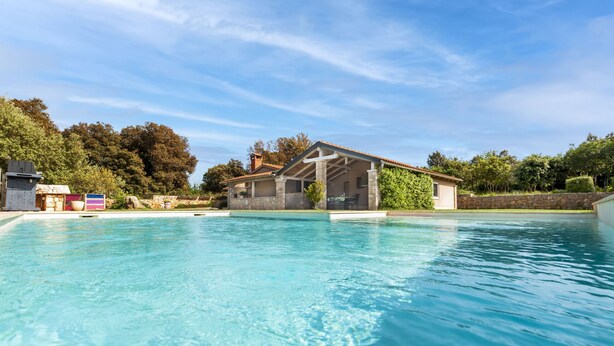 Una piscina con una casa de piedra al fondo.