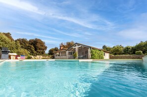 Una piscina con una casa de piedra al fondo.